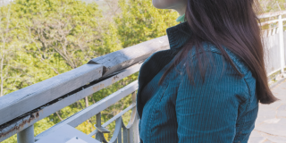 Photo d'une femme qui est dans un parc et qui lit avec ses mains des indications en braille sur le lieu où elle se trouve