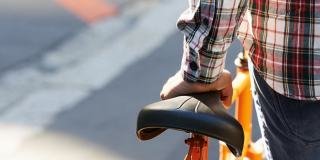 photo d'un jeune homme que l'on voit de dos poussant un vélo