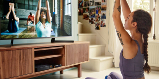 Jeune femme suivant un cours de yoga dans son salon face à la TV